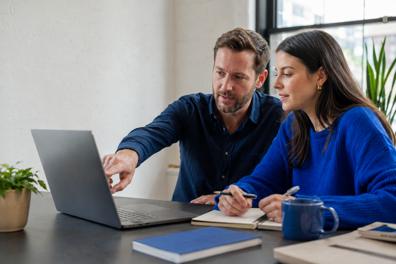 Two teammates reviewing search performance and a content plan on a laptop