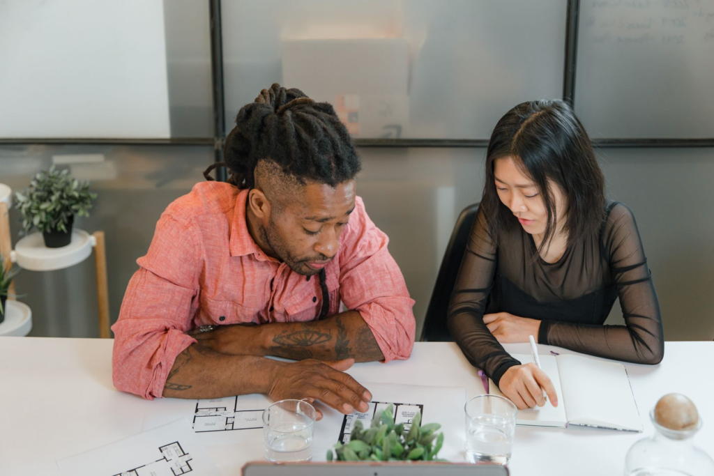 Two professionals discussing plans around a table